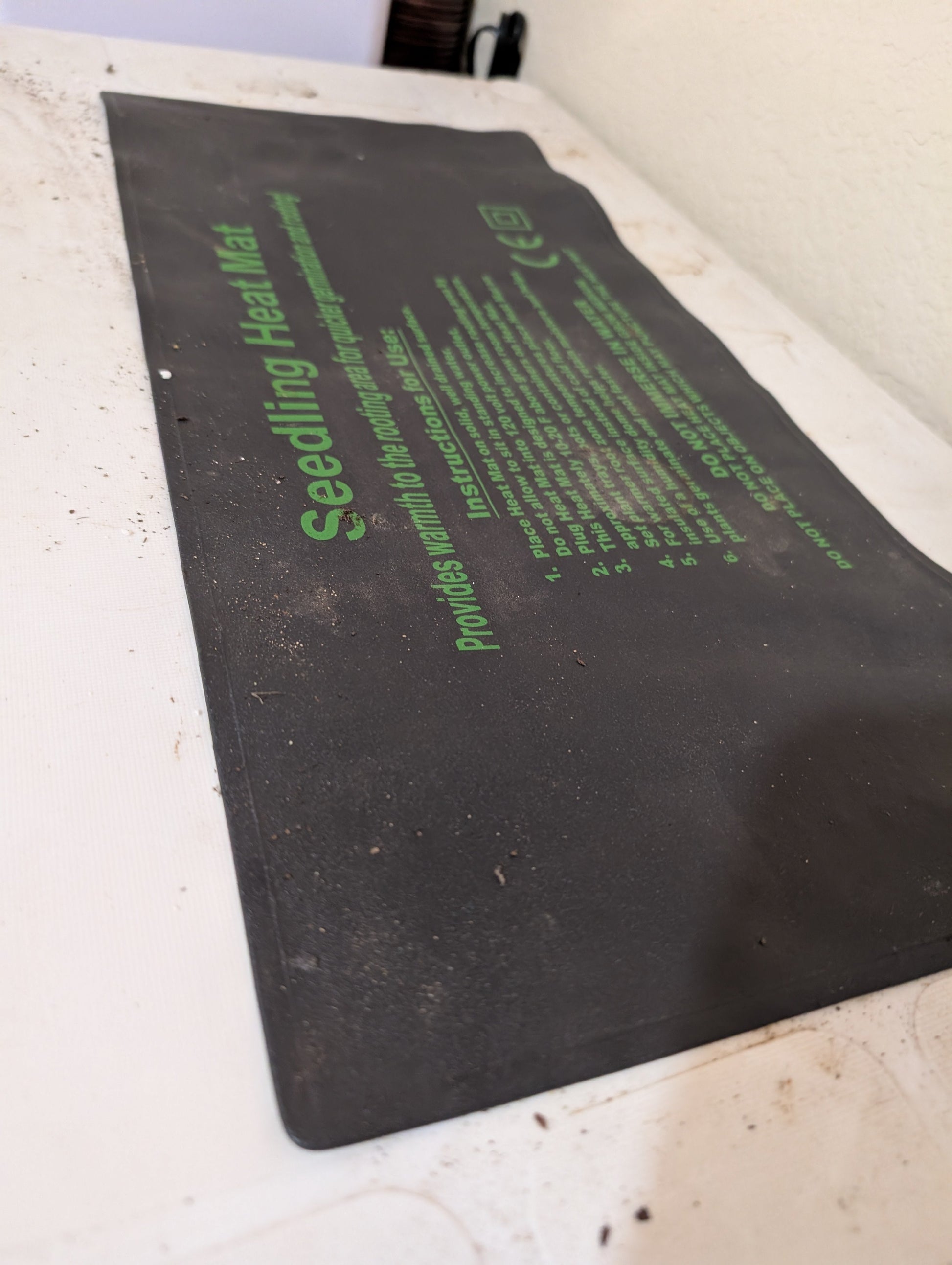 Hasty Roots seedling heat mat for gardening supplies, showing a close-up of the black mat with textured surface for plant propagation.