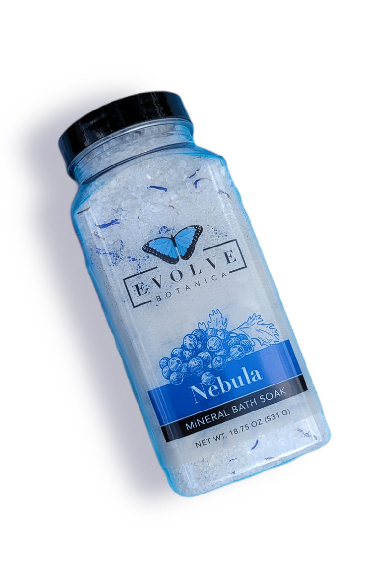 Evolve Botanica Mineral Soak Nebula bath salt in a clear jar with colorful crystals and natural botanical accents inside.