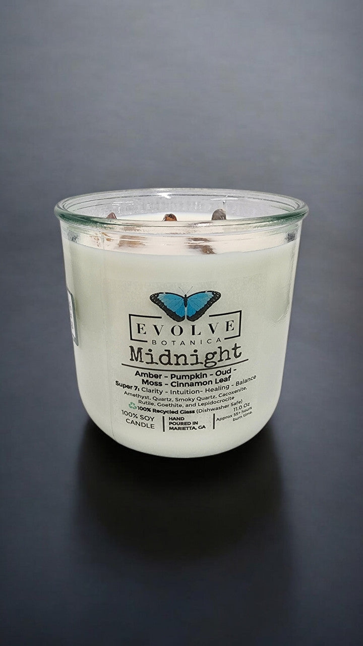Evolve Botanica Midnight Rocks Candle with wood wick and seven gemstones in a glass jar, showcasing a dark, elegant soy candle.
