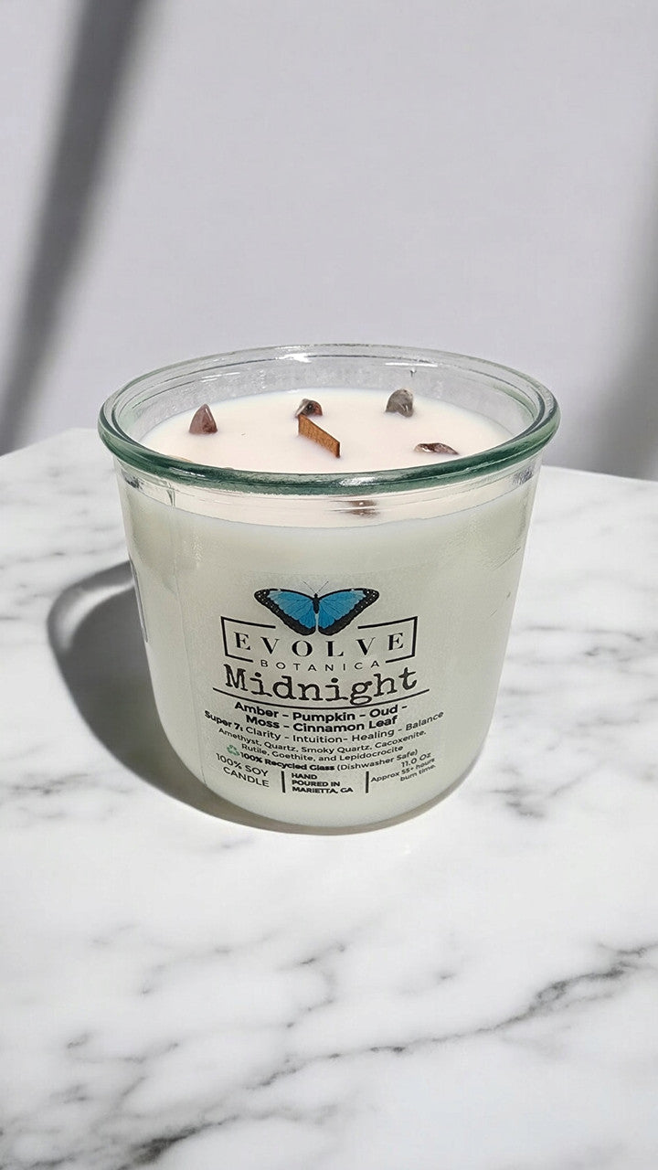 Evolve Botanica Midnight Rocks Candle with wood wick, featuring Super Seven gemstone soy candle in a decorative jar.