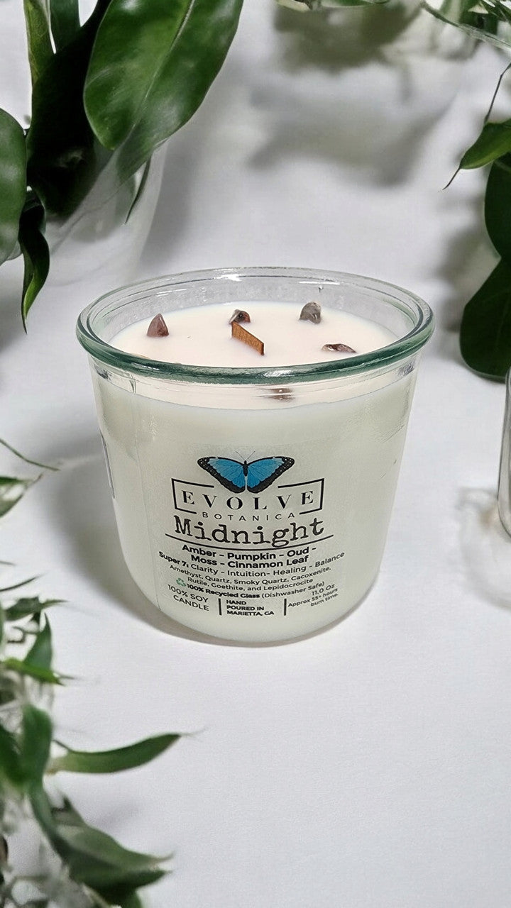 Evolve Botanica Midnight Rocks Candle with wood wick and seven gemstones, soy wax, dark jar, and decorative stones.