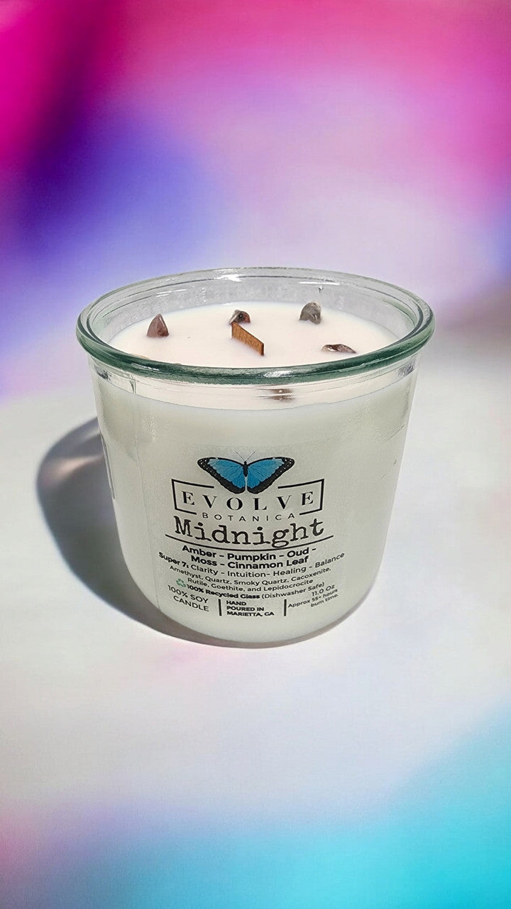 Evolve Botanica Midnight Rocks Candle with wood wick and Super Seven gemstone, soy wax, dark color, and textured surface.