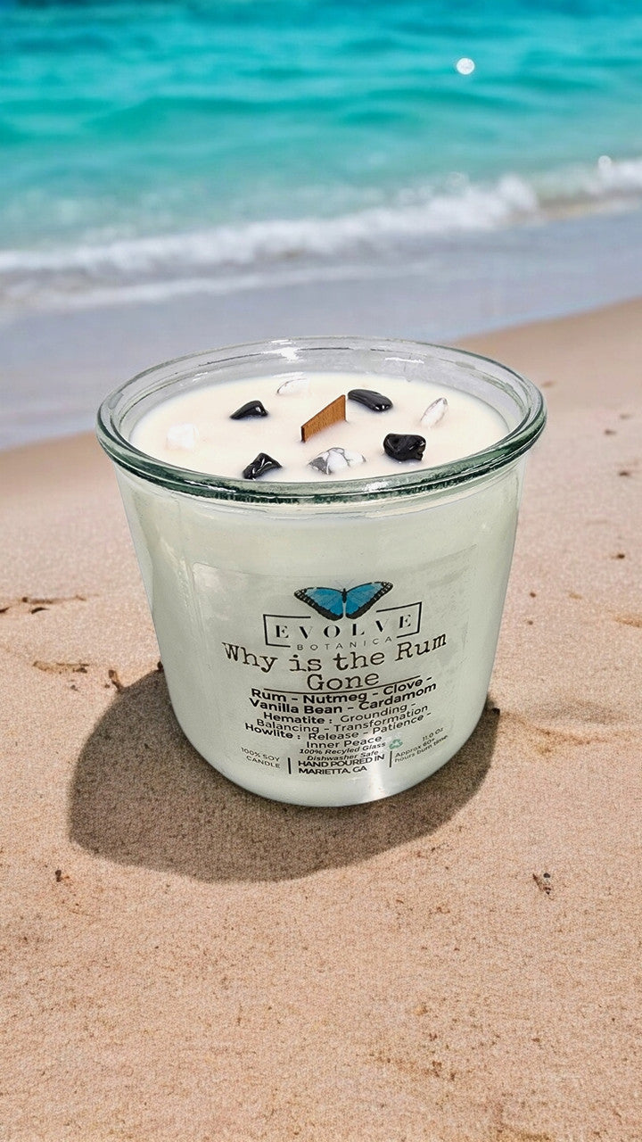 Evolve Botanica Rocks Candle "Why Is The Rum Gone?" with hematite and howlite stones, featuring a wood wick for soothing ambiance.