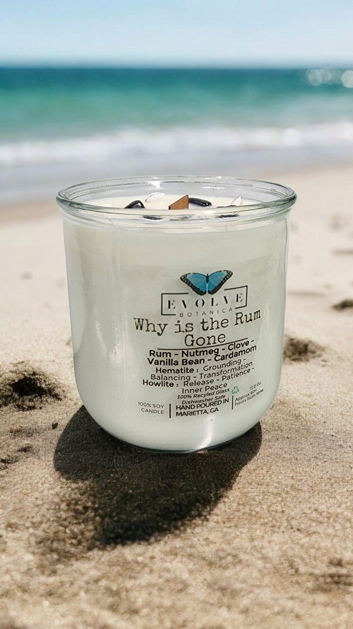 Evolve Botanica Rocks Candle "Why Is The Rum Gone?" with hematite and howlite stones, featuring a wood wick for grounding and relaxation.