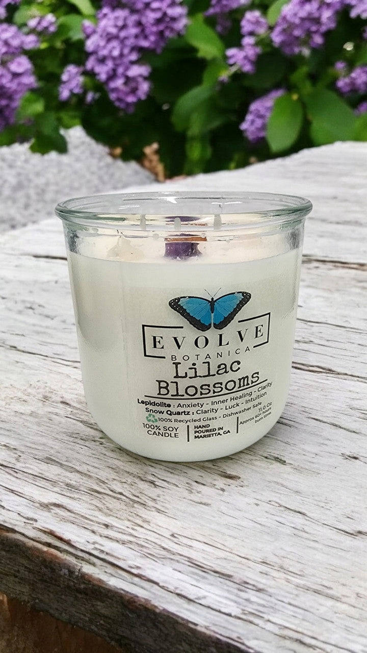 Evolve Botanica Rocks Candle Lilac Blossoms with wood wick and Lepidolite gemstone, soy wax in a clear glass jar.