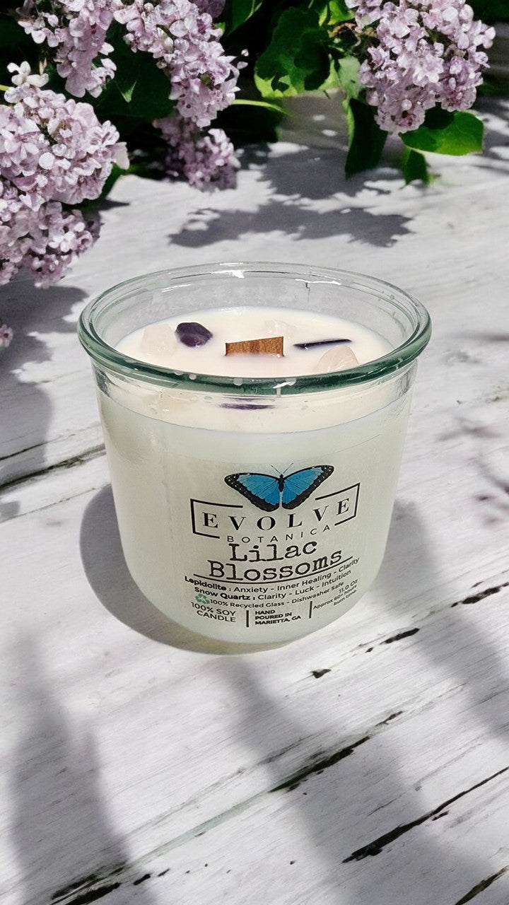 Evolve Botanica Rocks Candle with Lilac Blossoms scent, wood wick, and Lepidolite gemstone in a soy candle jar.