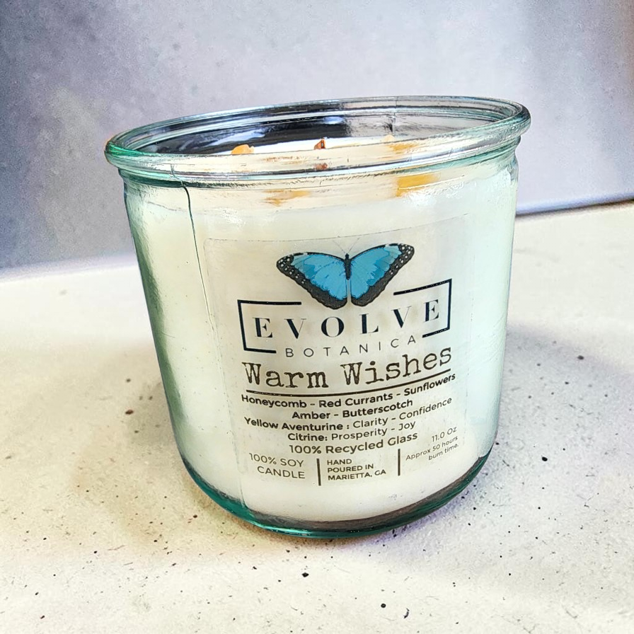 Evolve Botanica Rocks Candle Warm Wishes with wood wick, citrine and aventurine gemstones, in a cozy soy candle setting