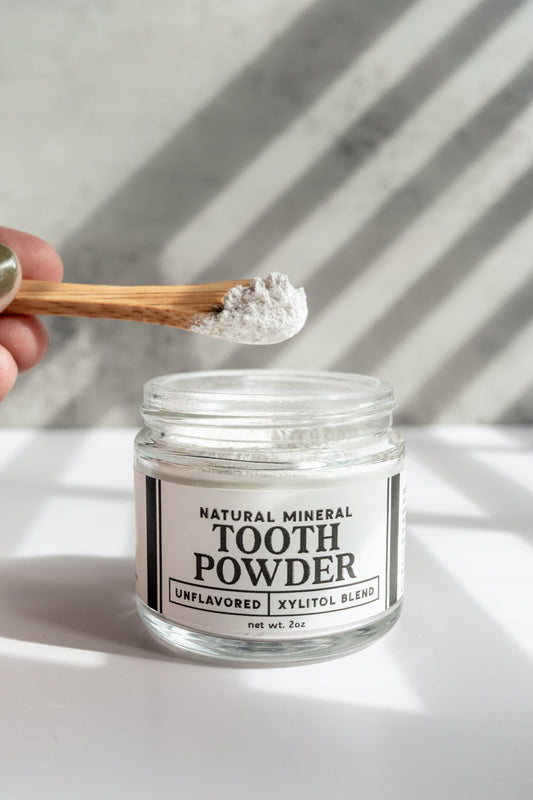 Remineralizing tooth powder with hydroxyapatite and xylitol in a natural container, designed for dental health and enamel restoration.