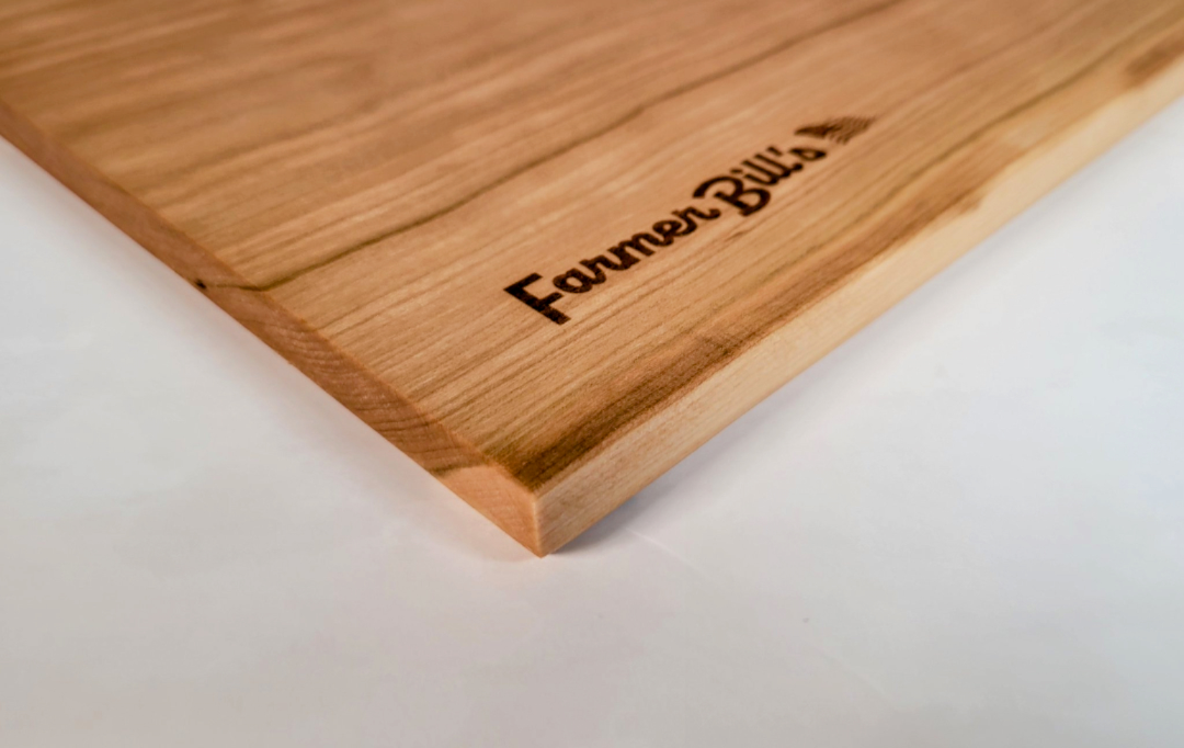 Cherrywood cutting board made by Farmer Bill's Provisions, showcasing a smooth, polished surface and natural wood grain.