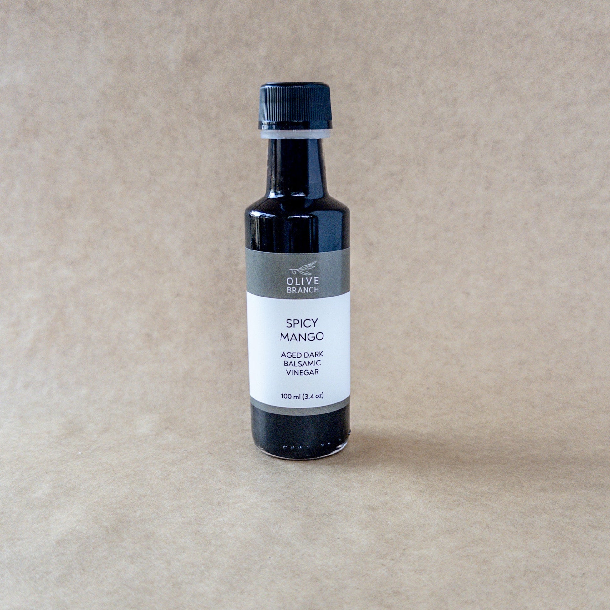 Dark balsamic vinegar with spicy mango flavor from Olive Branch Oil & Spice, featuring a deep amber color in a glass bottle.