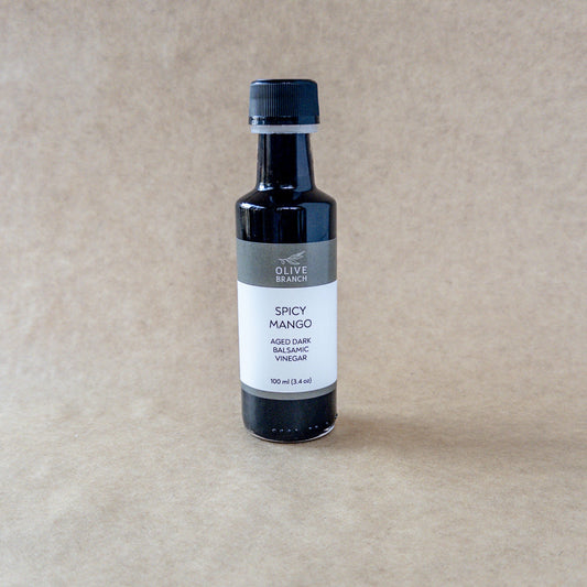 Dark balsamic vinegar with spicy mango flavor from Olive Branch Oil & Spice, featuring a deep amber color in a glass bottle.