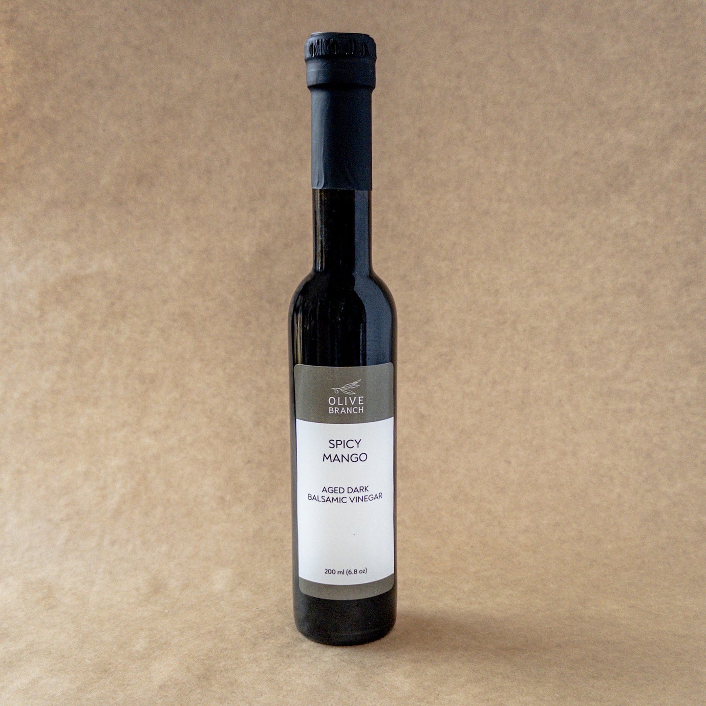 Dark balsamic vinegar with spicy mango flavor from Olive Branch Oil & Spice, showcased in a glass bottle with a pour spout.