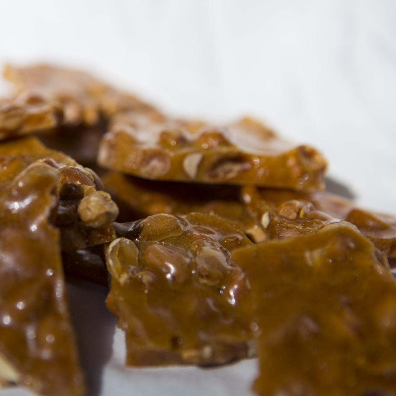 Homemade peanut brittle in an 8 oz serving from Sweets by Suzanne, showing golden, crunchy caramelized peanuts.
