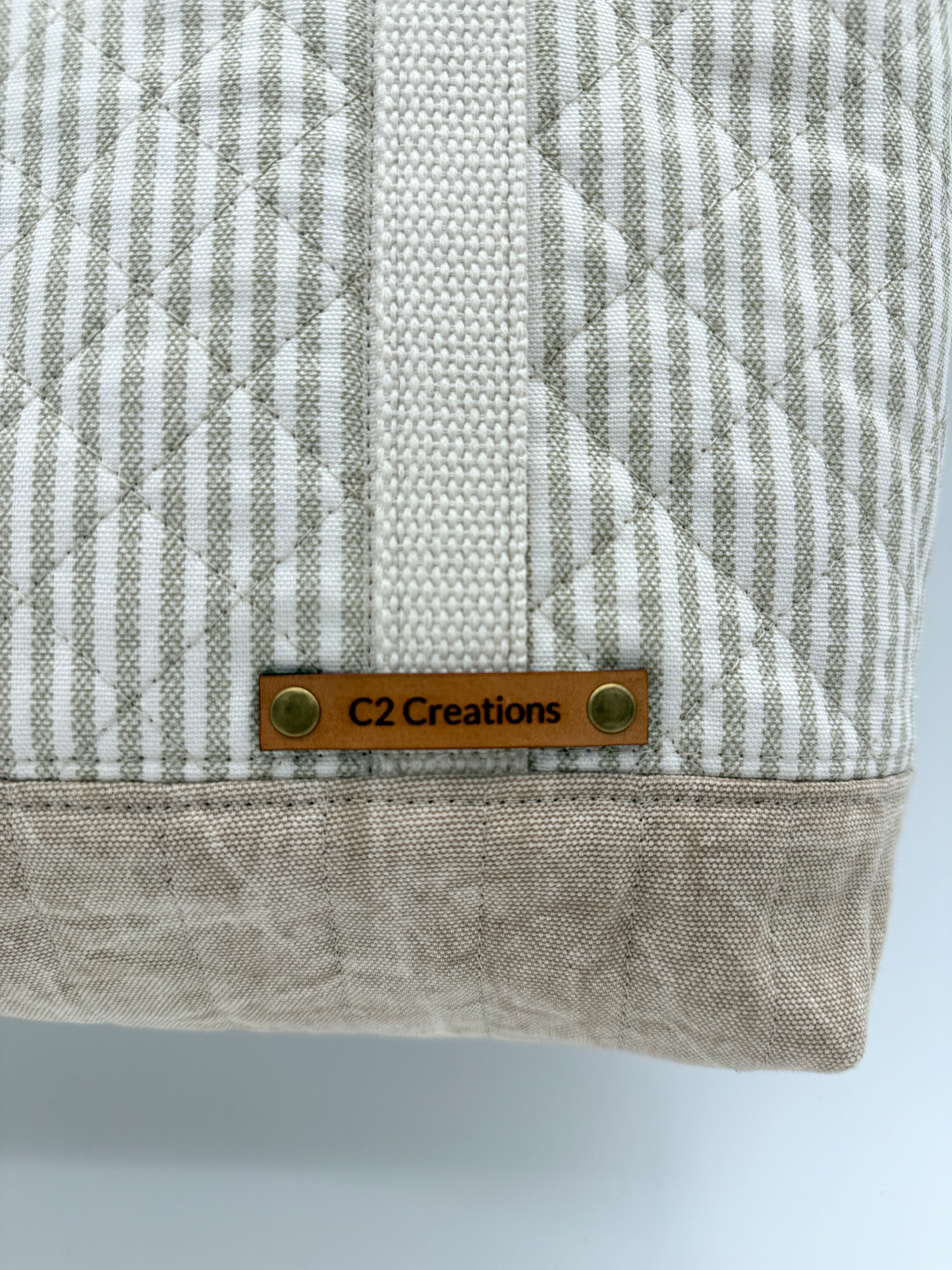 Close-up of a handmade taupe stripe quilted canvas tote bag with snap closure by C2 Creations LLC.