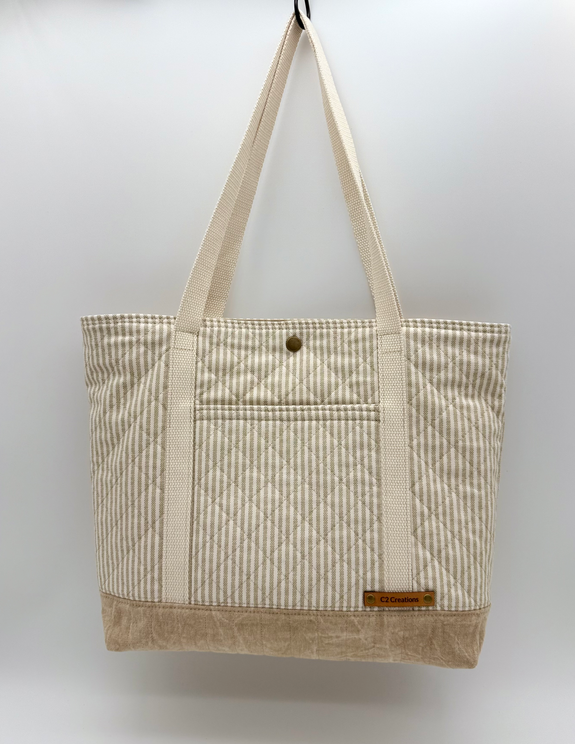 Taupe striped quilted canvas tote bag with snap closure, handmade by C2 Creations LLC, front view showing handles and stitching details.