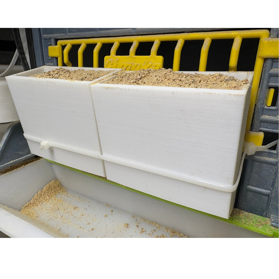 Two adjustable spill-resistant button quail feeders by Quailz.com, made in the USA, showing front slot design for animal husbandry.