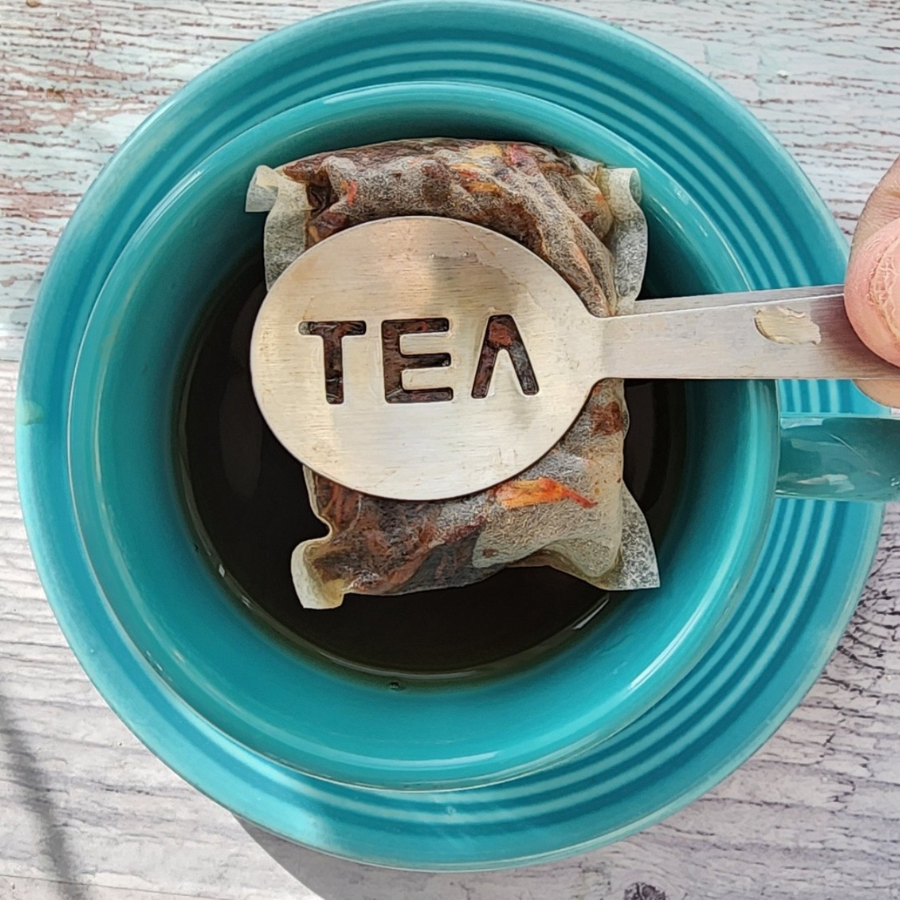 Cold brew black strawberry tea in a glass pitcher with two tea bags, brewed for a refreshing, caffeinated beverage.