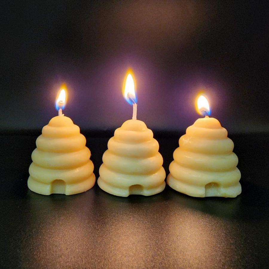 Bees wax candle in a small 2 oz jar, natural honey color, from Buzz Savories, LLC, with a simple, rustic appearance.