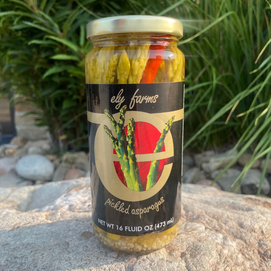 Glass jar of Ely Farms pickled asparagus spears in a 16 oz container, showcasing fresh green asparagus immersed in pickling liquid.