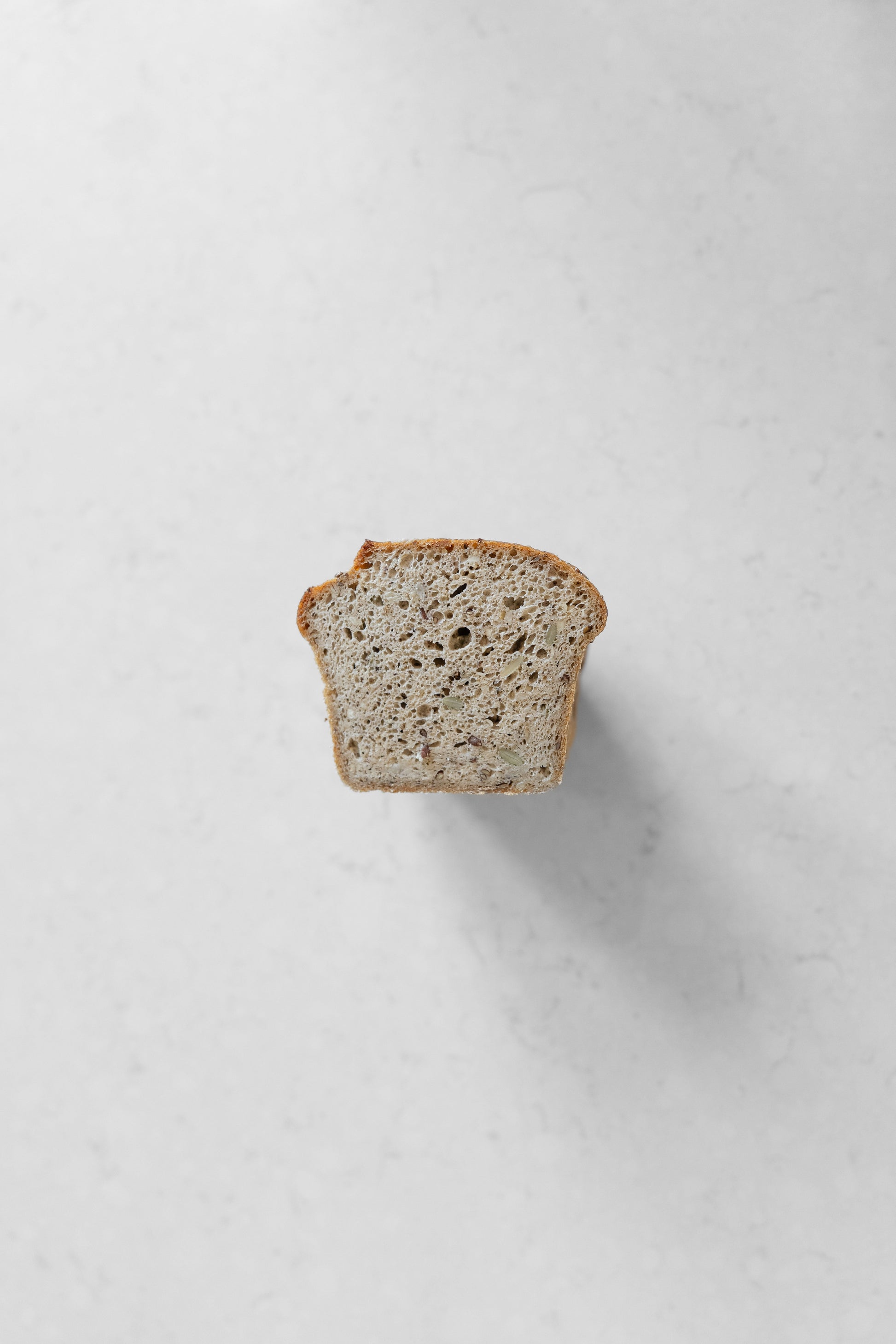Heaven Gluten Free Bakery multi-seed sourdough vegan loaf with visible seeds and crust on a cutting board.