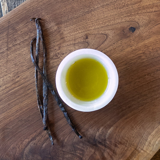 Bottle of Vanilla Bean Infused Extra Virgin Olive Oil from Olive Branch Oil & Spice, showing the infused oil with vanilla beans inside.
