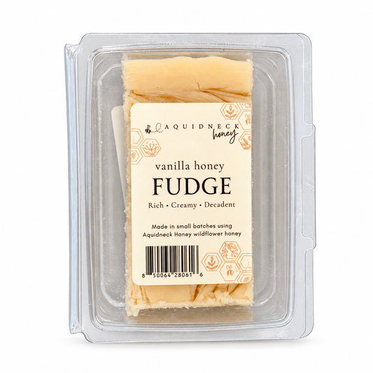 A clear clamshell containing Aquidneck Honey vanilla honey fudge, showing its creamy texture and rich vanilla flavor.