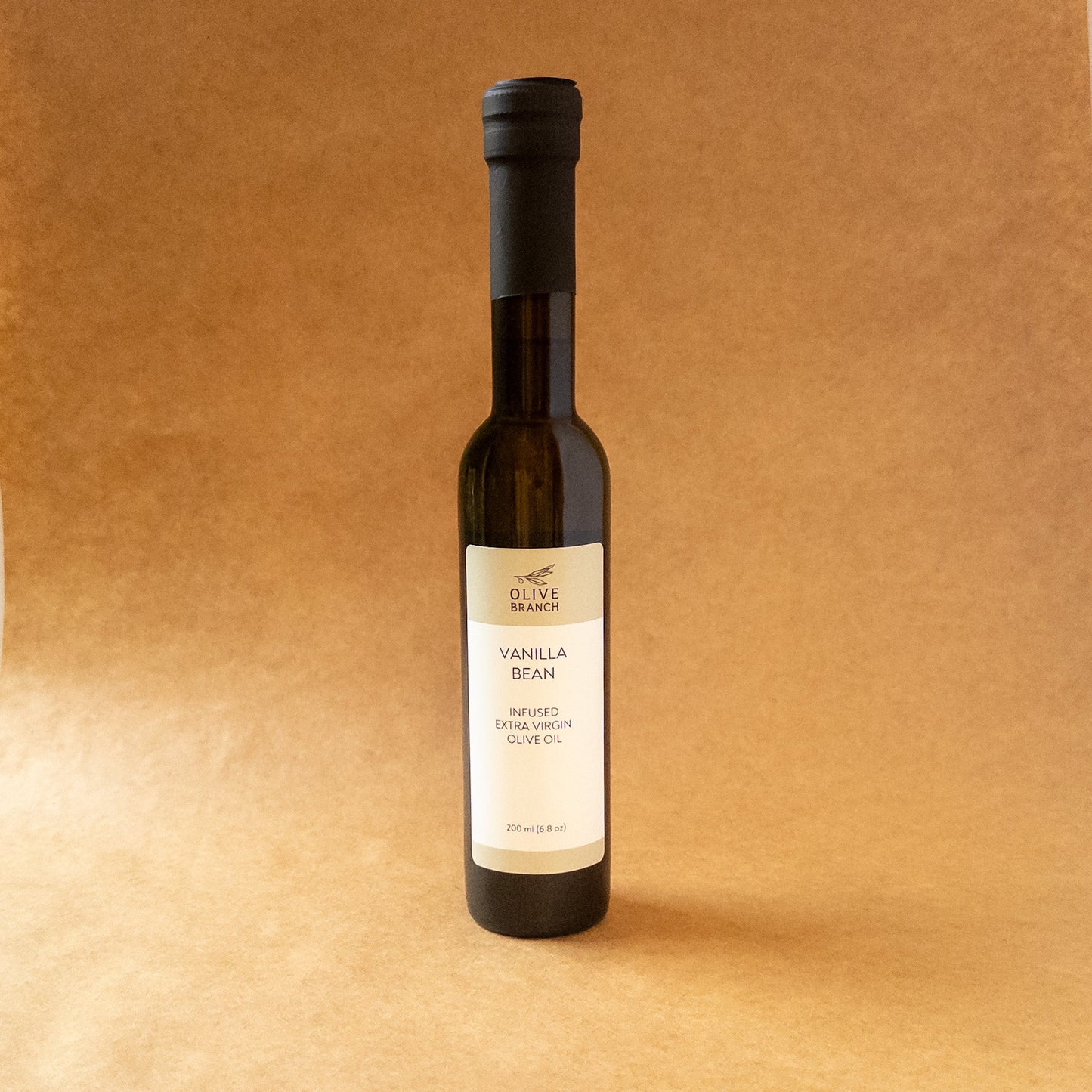 Bottle of Vanilla Bean Infused Extra Virgin Olive Oil from Olive Branch Oil & Spice, showcasing the infused oil with vanilla beans inside.