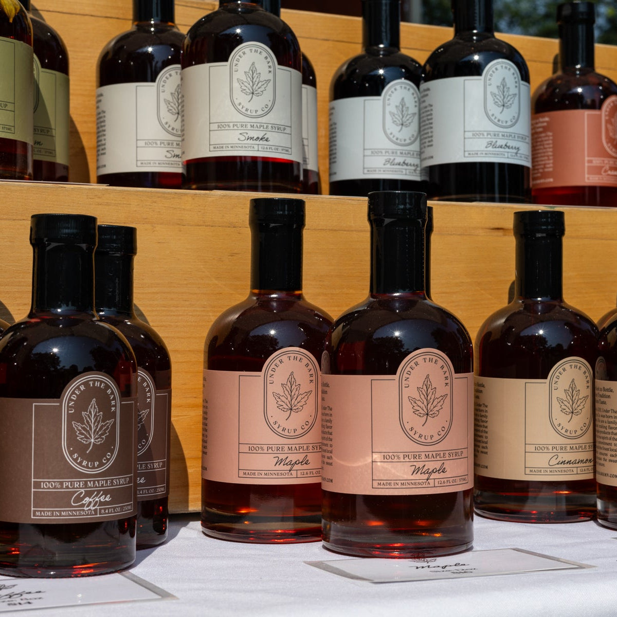 Bottle of Smoke Maple Syrup by Under The Bark Syrup Co, showcasing rich, dark syrup in a glass jar with a wooden cap.