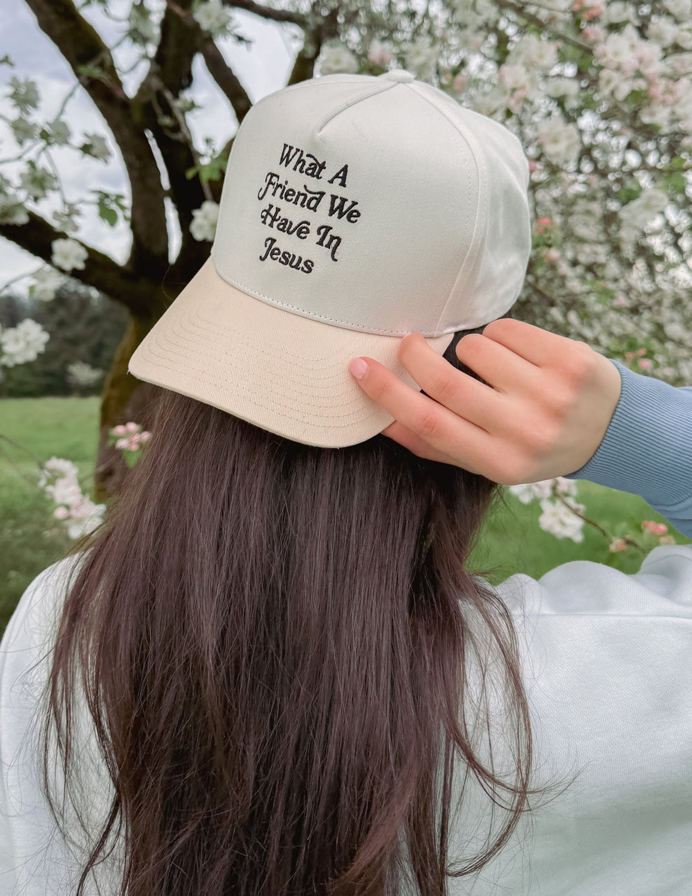 Elevated Faith trucker hat featuring the phrase "What a Friend in Jesus" embroidered on the front in black and white.