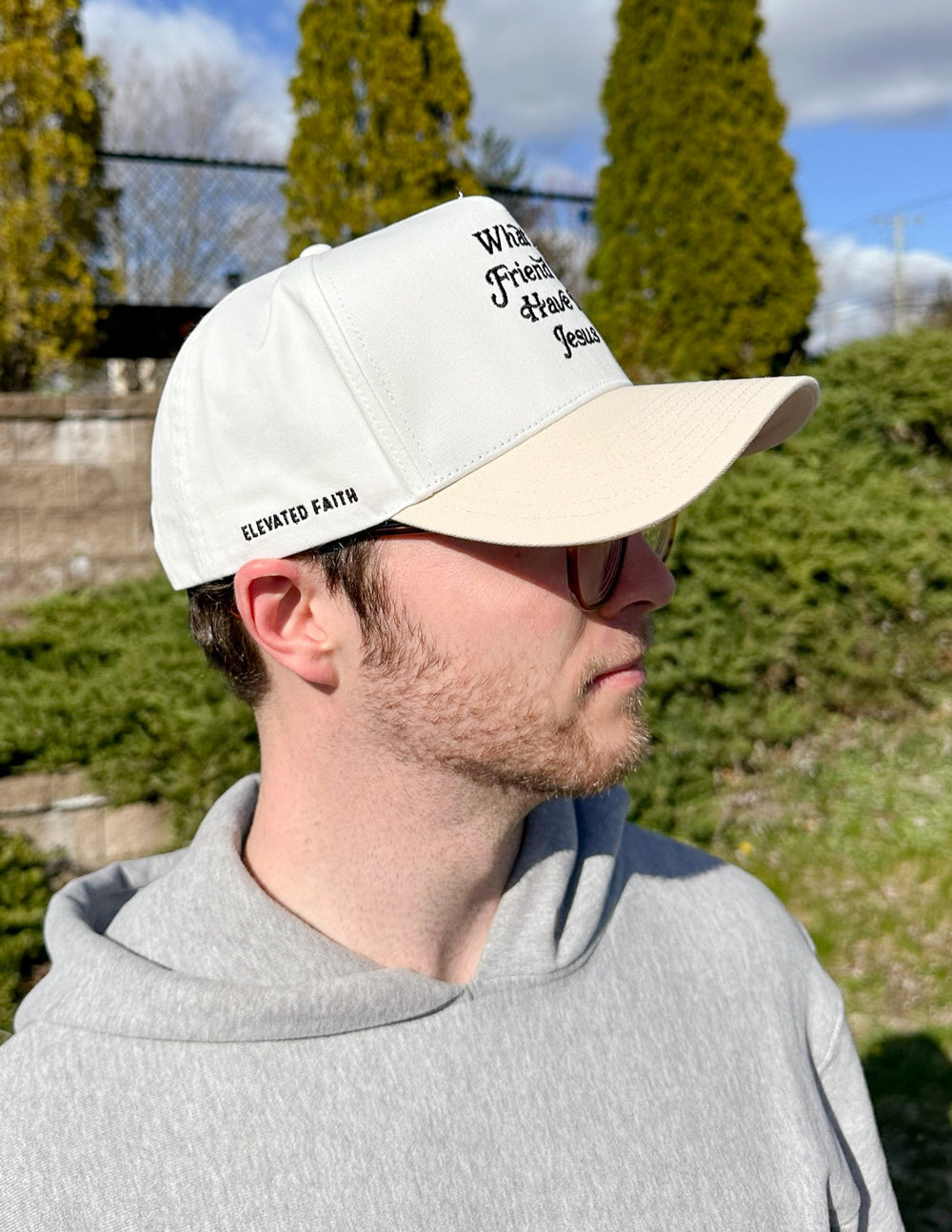 Raised front trucker hat with "What a Friend in Jesus" embroidered design, featuring a mesh back and adjustable snap closure.
