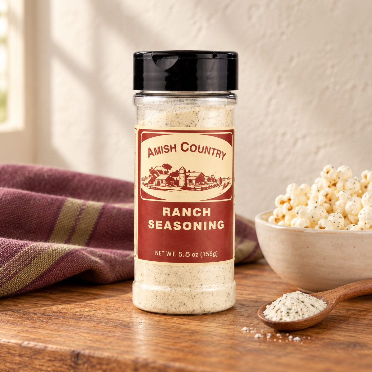 Amish Country Store Ranch Popcorn Seasoning packet next to Amish popcorn bag on a wooden table.