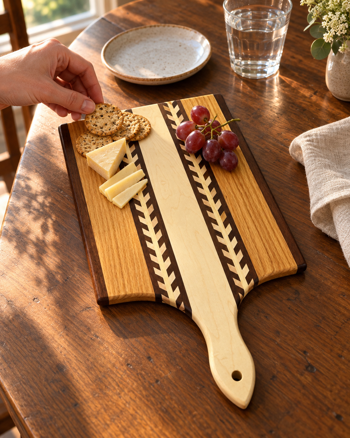 Amish Handmade Wheat Inlay Cutting Board with mixed hardwood paddle, showing intricate wheat design on a kitchen surface.