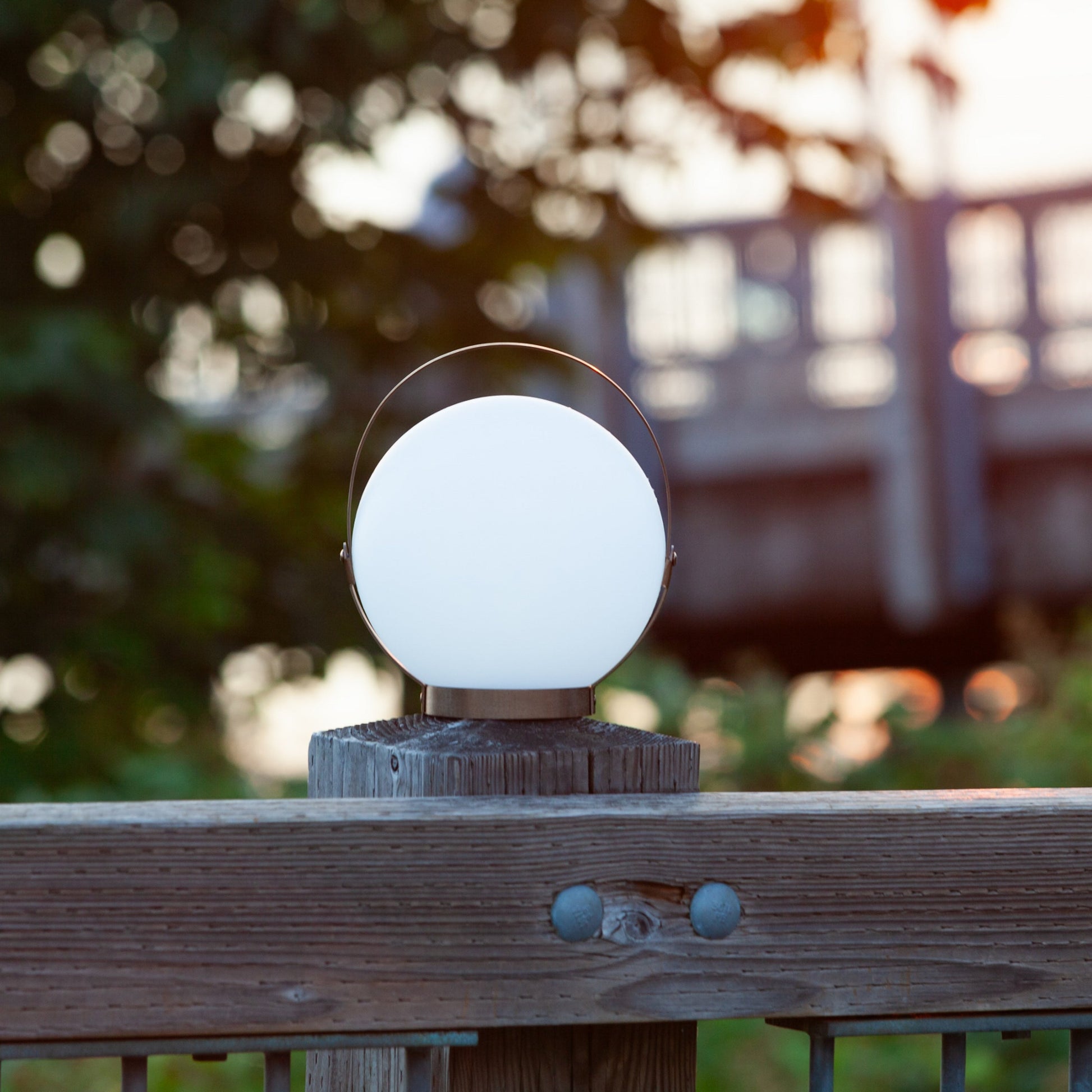 Allsop Home & Garden Moonrise portable rechargeable LED lantern with handle, glowing in a soft white light.