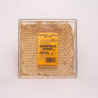 Small New England hand-cut honey comb from Aquidneck Honey, showcasing golden honey and natural beeswax in a rustic frame.