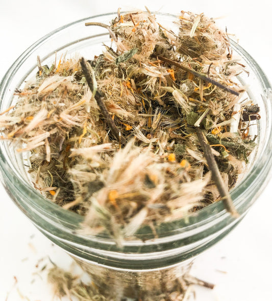 Small jar of dried arnica flowers in herbalroseapothecary herb jars collection, featuring white label and clear glass container.
