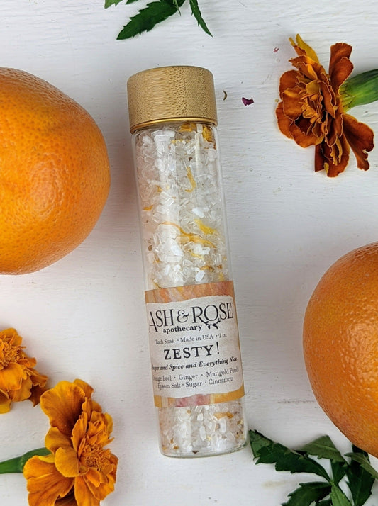 Ash & Rose ZESTY! Orange Ginger bath soak vial with vibrant orange liquid and a natural, aromatic appearance.
