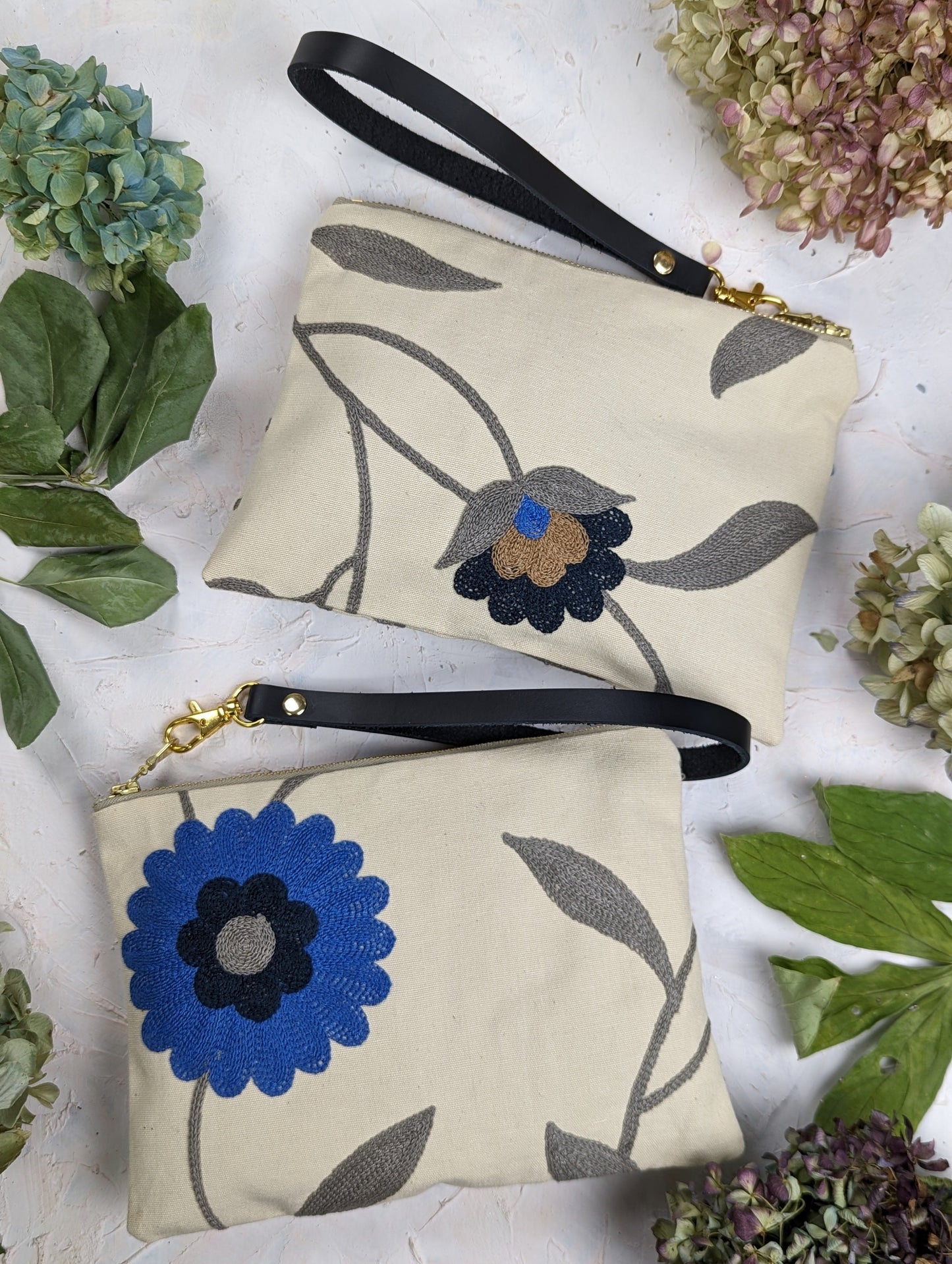 Blue Poppy wristlet purse by Ash & Rose featuring a compact design and floral pattern, with a zipper closure and wrist strap.