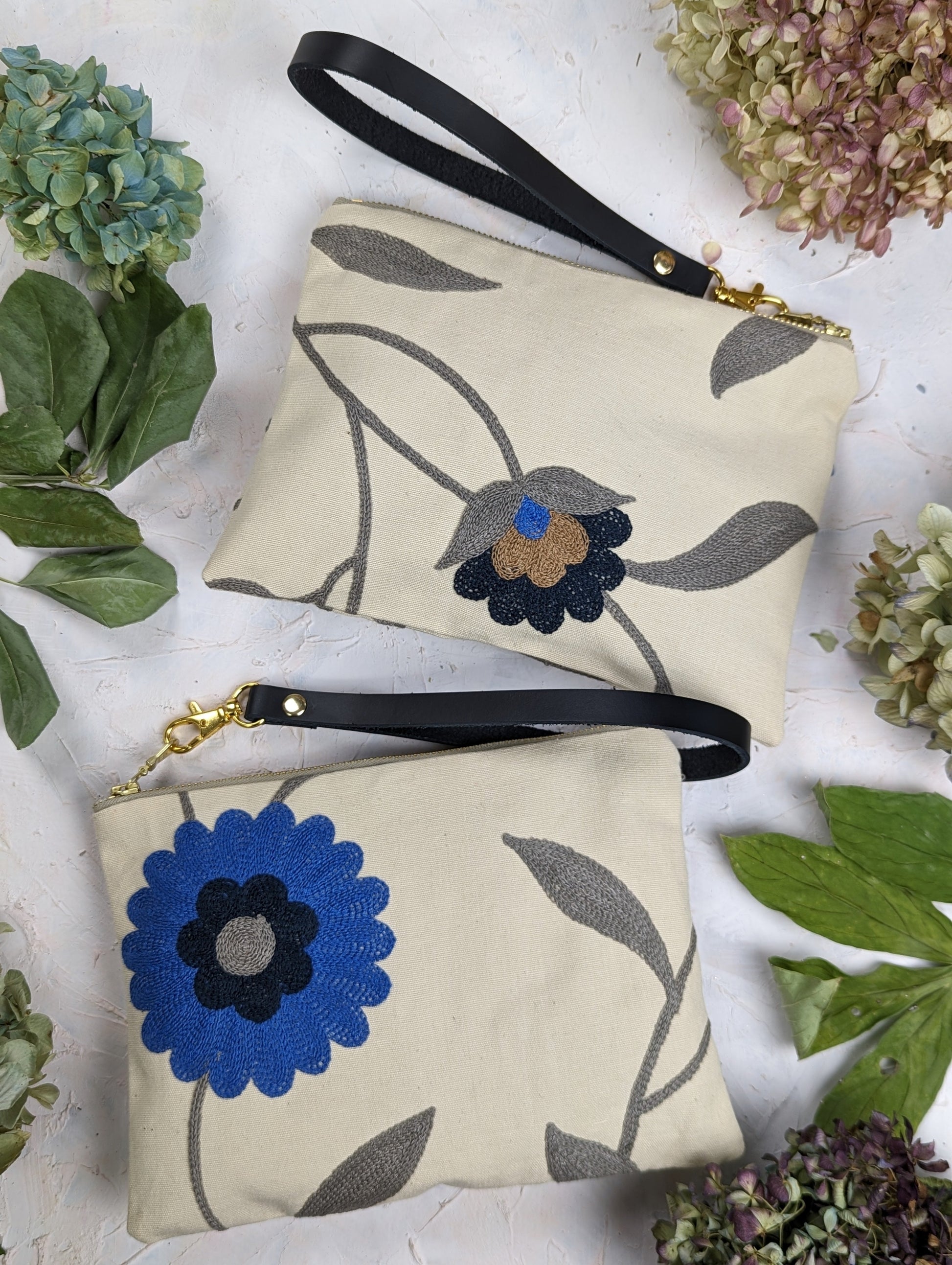 Blue Poppy wristlet purse by Ash & Rose featuring a compact design and floral pattern, with a zipper closure and wrist strap.