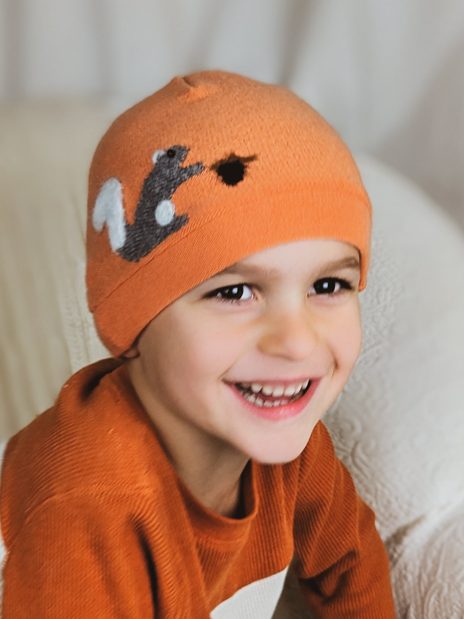 Child's orange cashmere squirrel hat by Ash & Rose, featuring a cozy knit design with a cute squirrel detail.