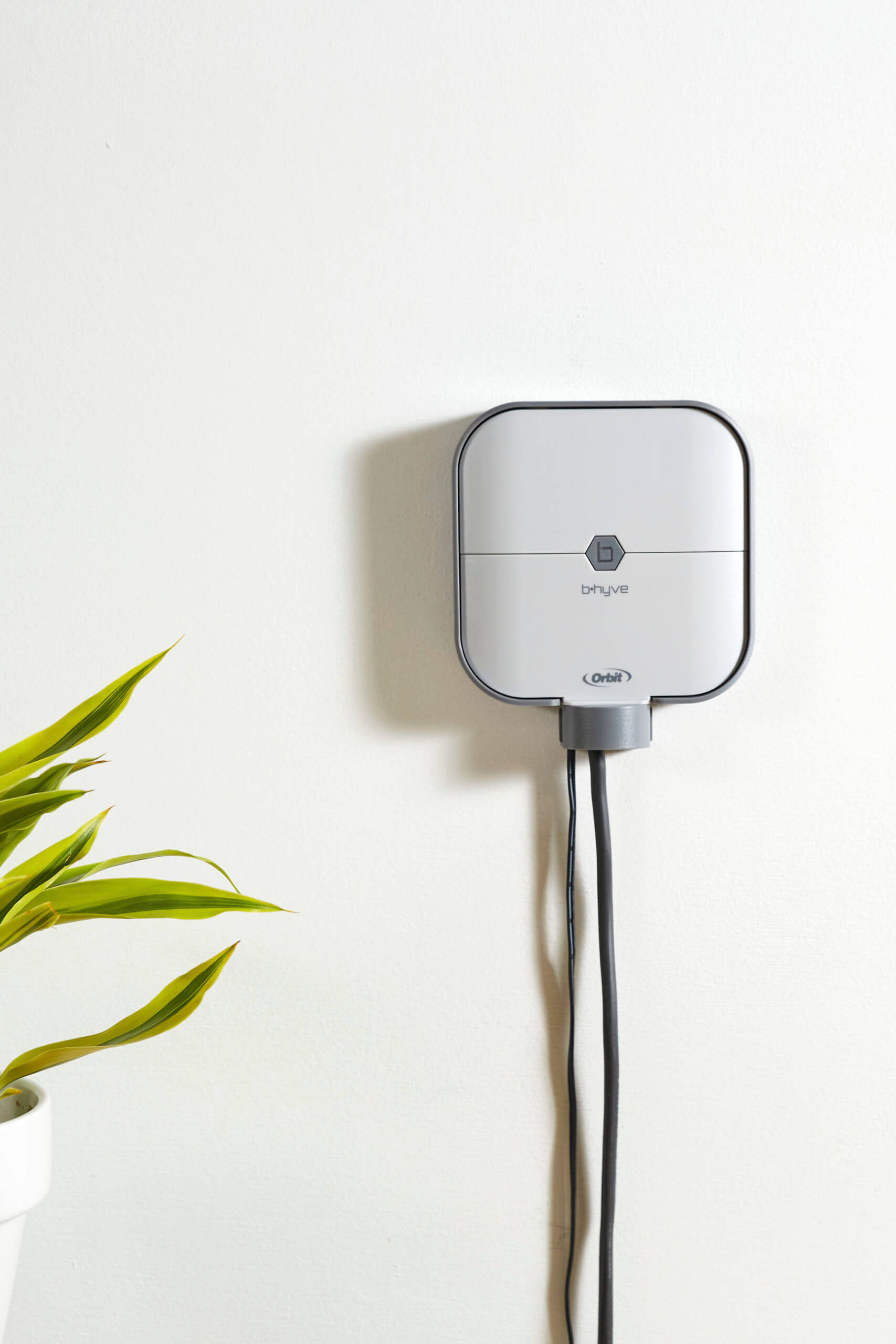 Orbit Irrigation B-hyve Smart Indoor Irrigation Controller mounted on a wall, digital display and control buttons for sprinkler timing.
