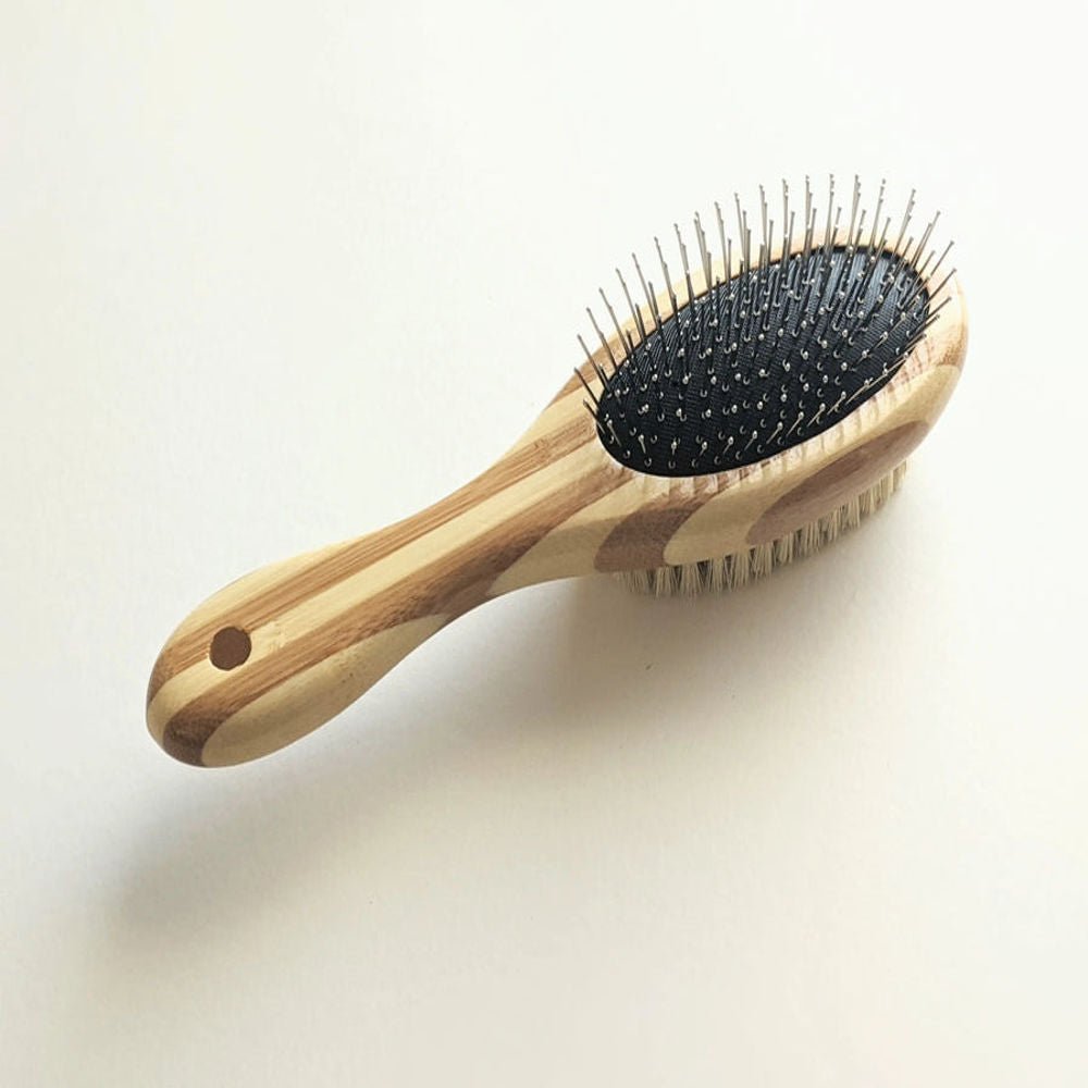 Double-sided Tilley + Me dog grooming brush with bamboo handle, featuring bristle and wire sides for shedding and detangling.