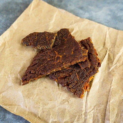 Thin slices of BBQ beef jerky from Nebraska Star Beef, showing a smoky, flavorful beef snack on a wooden surface.