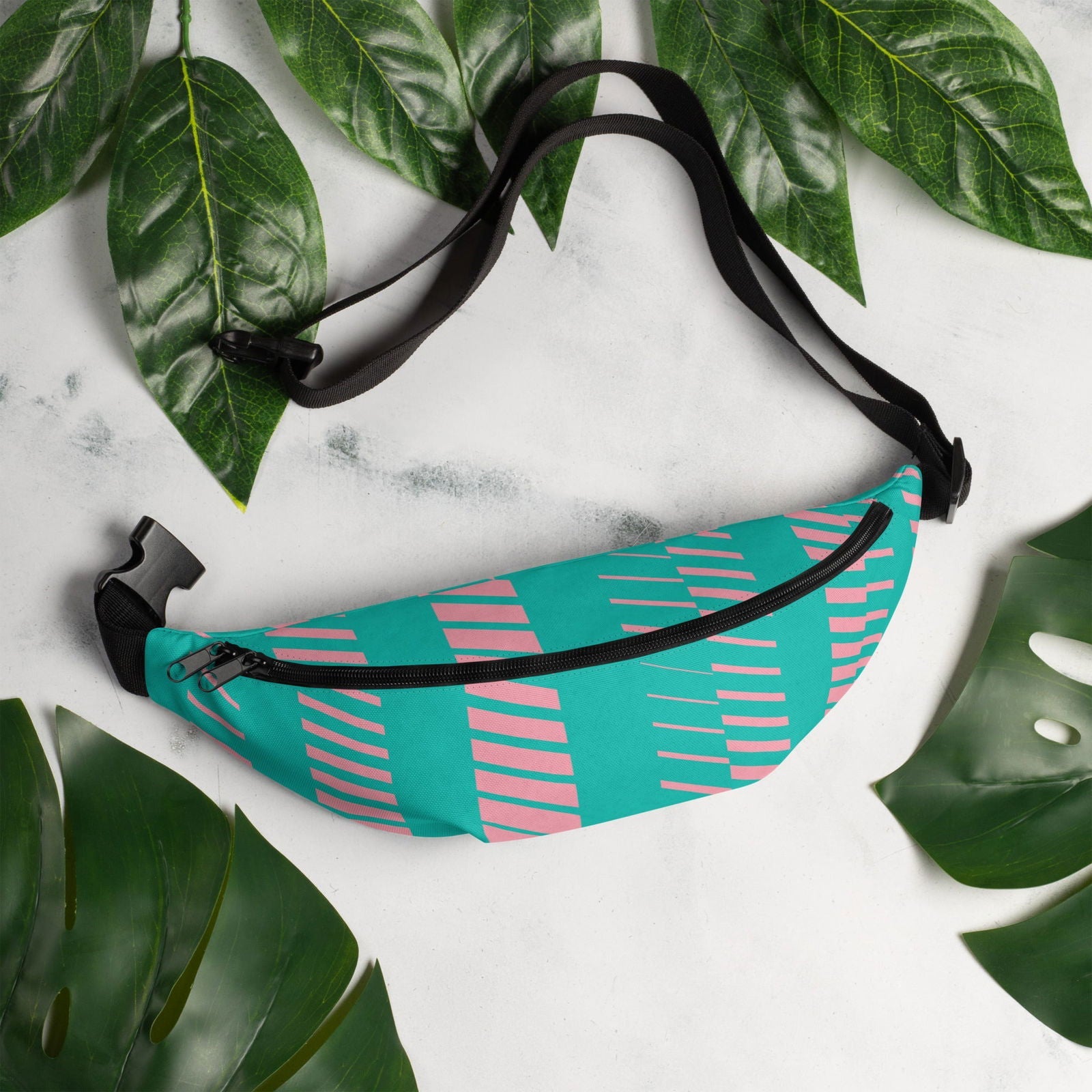 Pink and teal custom-designed Blessings Grow Meadows fanny pack with adjustable strap and colorful pattern, worn on a model.