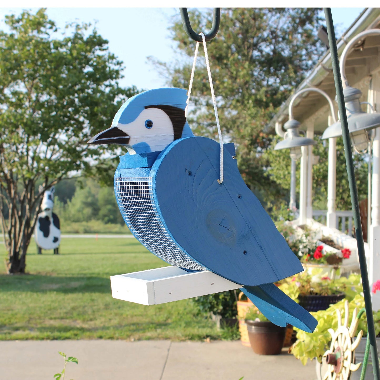 Bluejay perched on a handcrafted Amish-made wooden bird feeder, designed in a bird shape for garden decor.