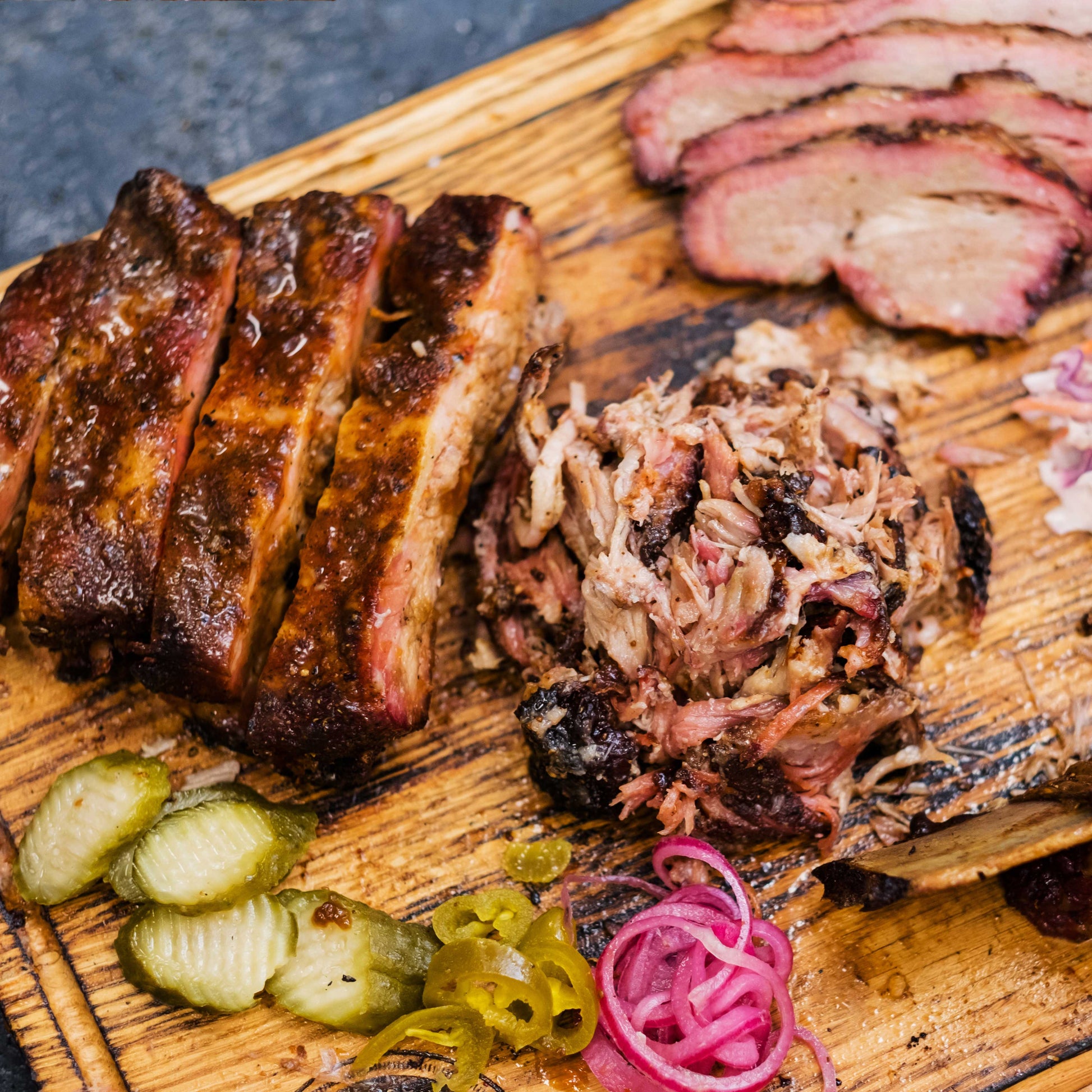 Pig of the Month BBQ Brisket and Ribs Feast with sliced brisket and ribs on a platter, perfect for feeding 6-8 people.