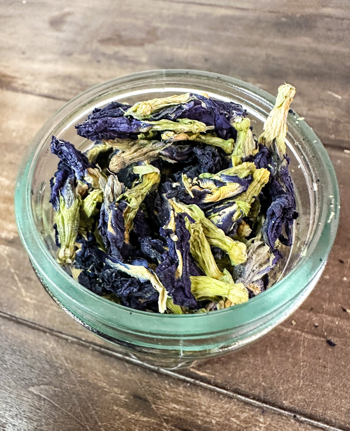 Small jar of dried butterfly pea flowers from herbalroseapothecary herb jars collection, showcasing vibrant blue dried herbs.