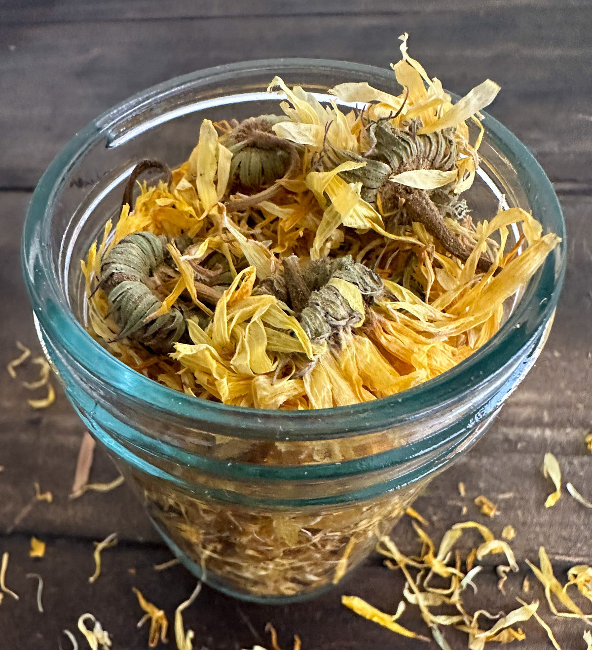 Small herbal jars from HerbalRoseApothecary filled with dried calendula herbs, showcasing vibrant orange petals in glass jars.