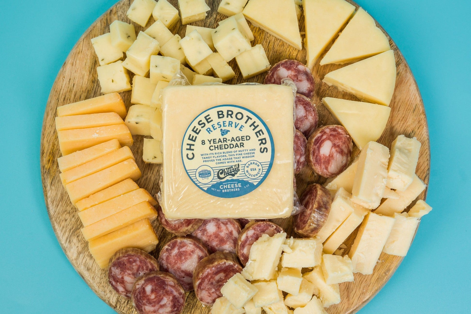 Cheese Brothers Deluxe Charcuterie Pack with assorted cured meats, cheeses, and accompaniments on a wooden board.