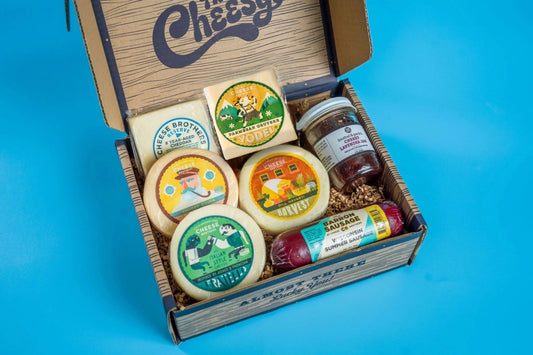 Assorted cheeses, cured meats, and accompaniments in a Cheese Brothers Inc. charcuterie box, perfect for gift or bundle presentation.