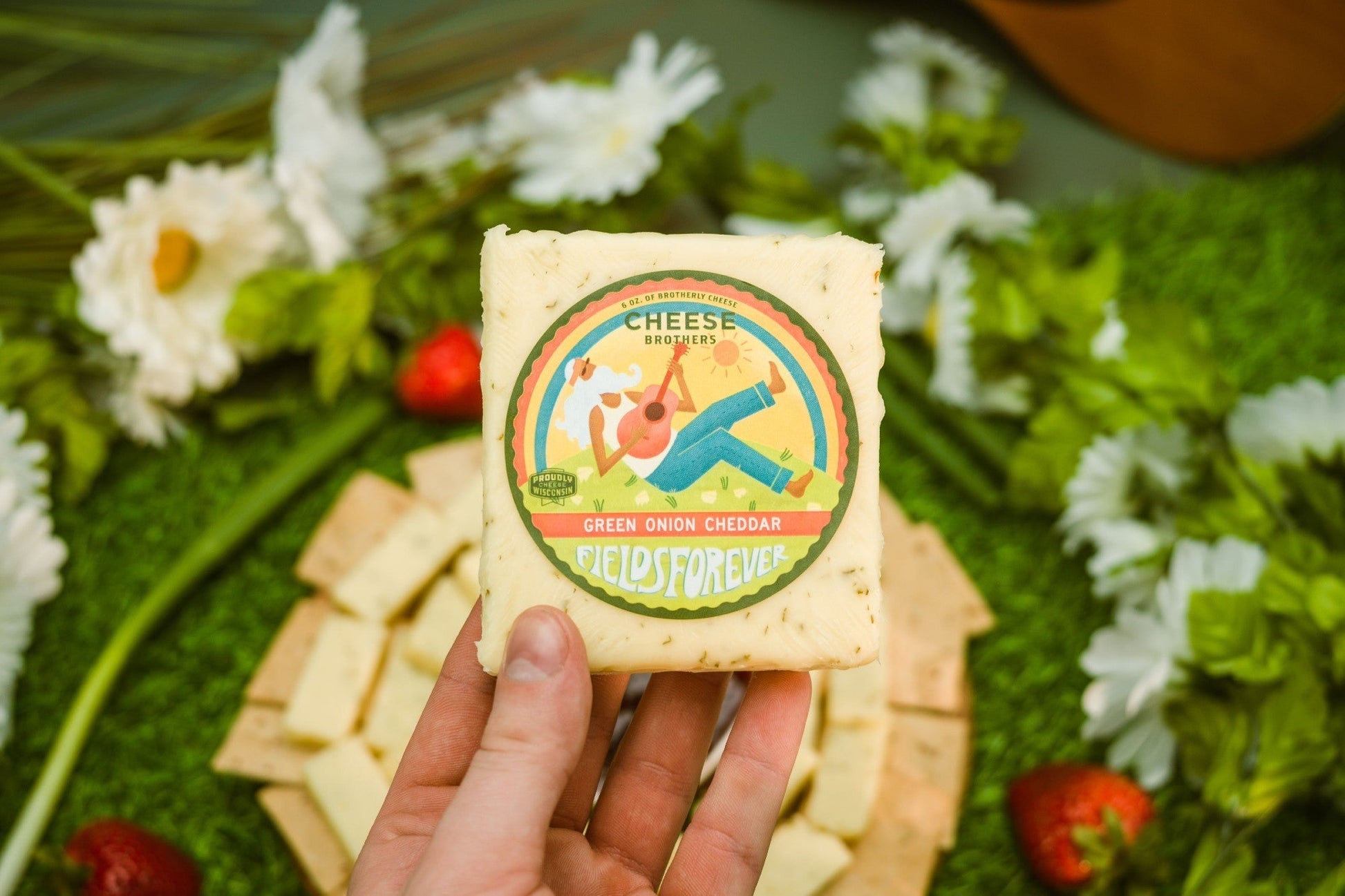 Slices of Green Onion Cheddar cheese from Cheese Brothers, Inc., showcasing vibrant green onions and rich cheddar texture.